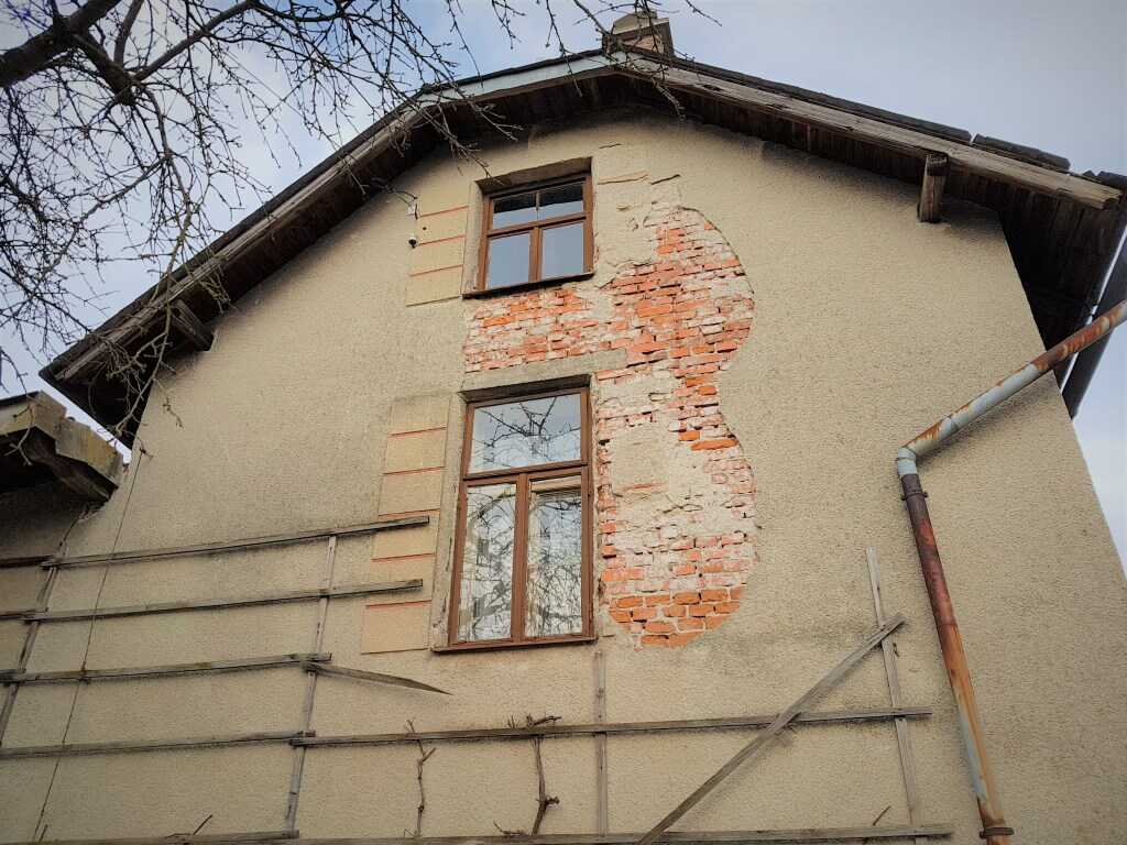Opadaná omítka na fasádě domu
