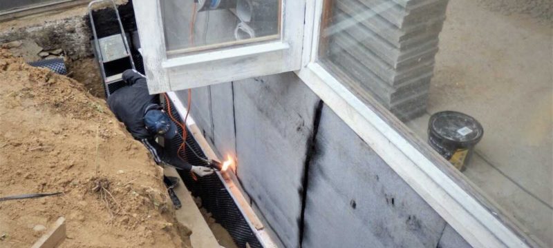 Hydroizolace základů domu asfaltovými pásy.